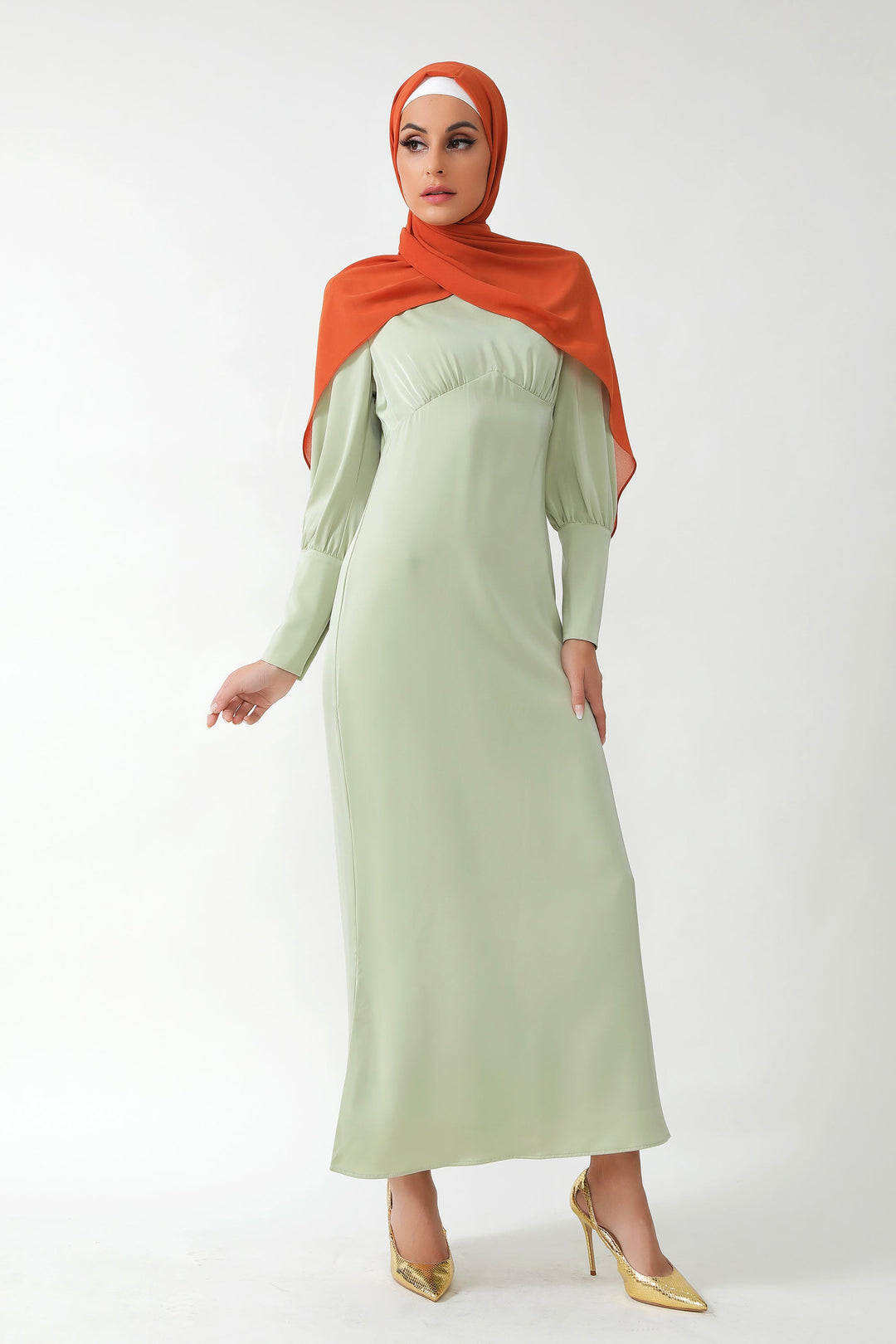 Woman wearing Pistachio Satin Long Sleeve Maxi Dress with batwing sleeves and orange hijab