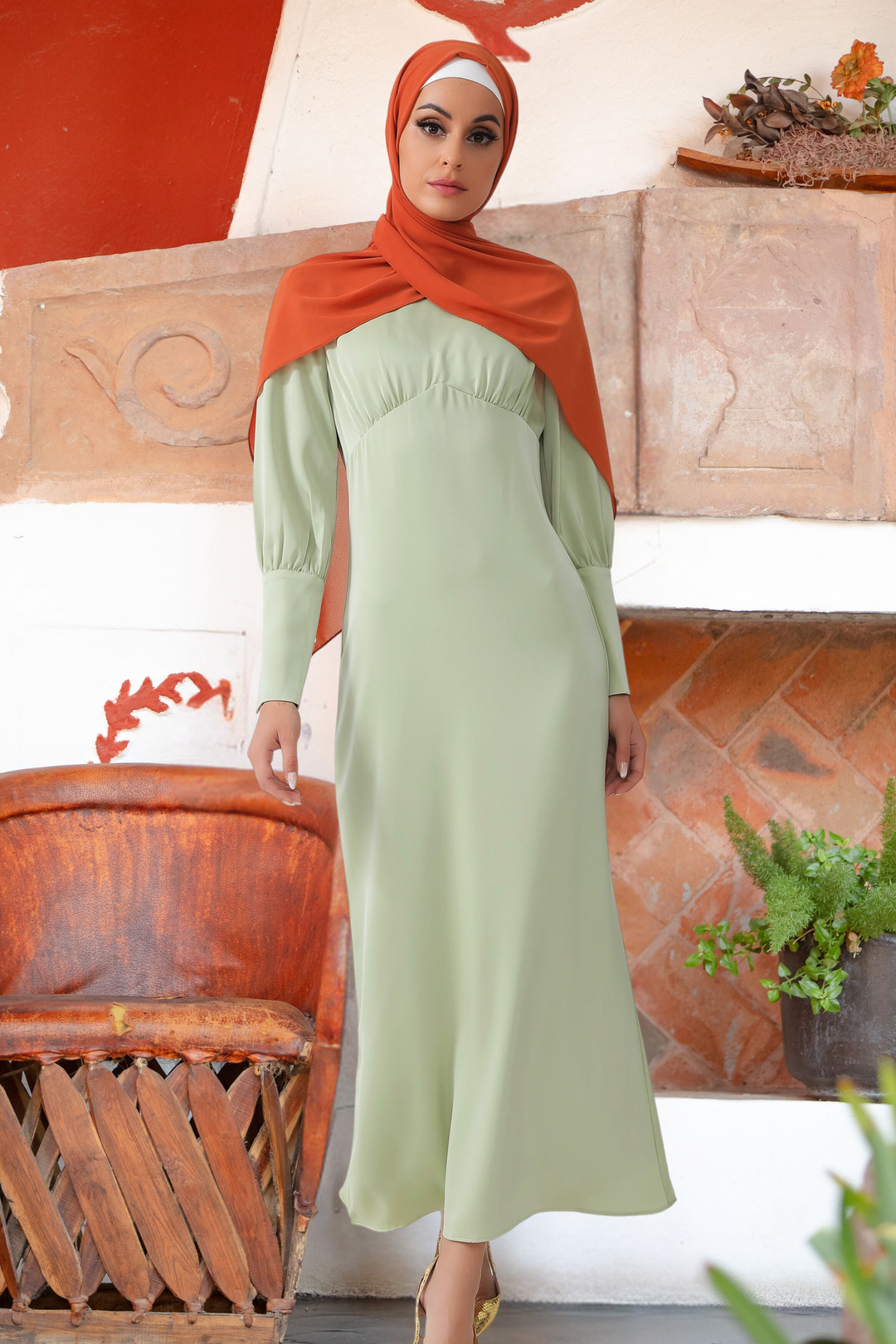 Woman in a light green Pistachio Satin Long Sleeve Maxi Dress with batwing sleeves