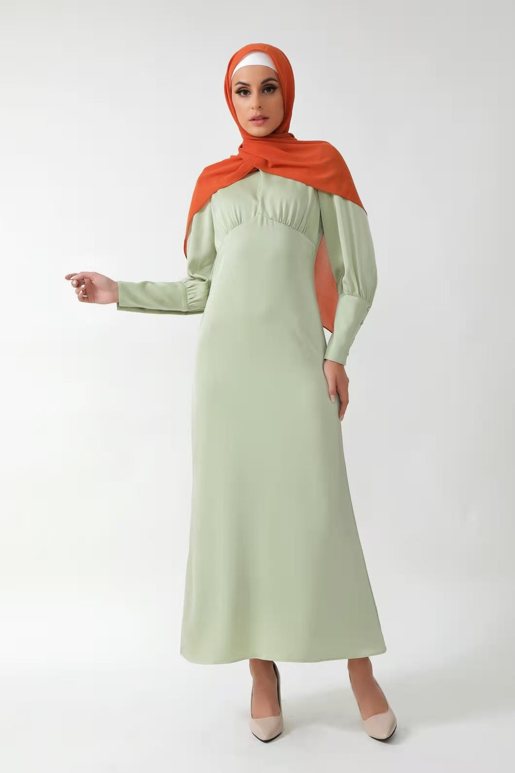 Woman in a Pistachio Satin Long Sleeve Maxi Dress with Batwing Sleeves and Orange Hijab