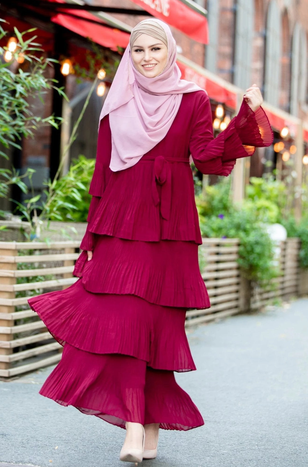 Woman in layered maroon dress with pink hijab featuring rhinestone trim chiffon