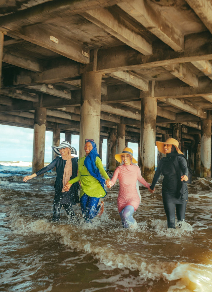 Four women in burkinis wearing the Ruched 3 Piece Modest Swimsuit for stylish beachwear