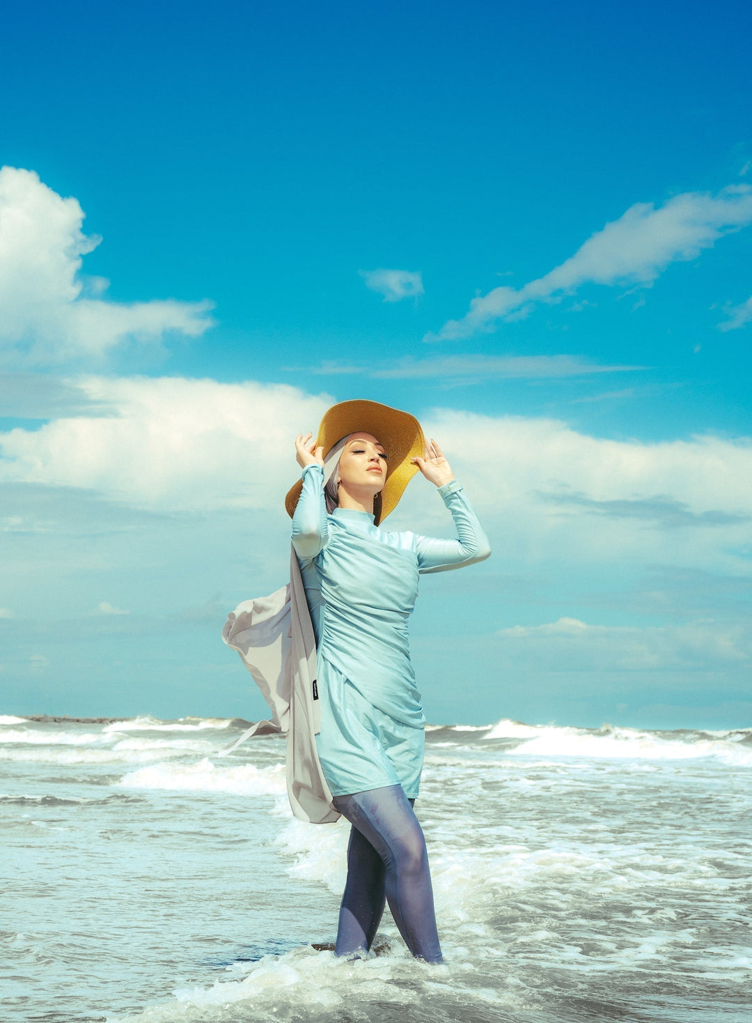 Woman in a burkini and sun hat wearing a stylish modest swimsuit on clearance