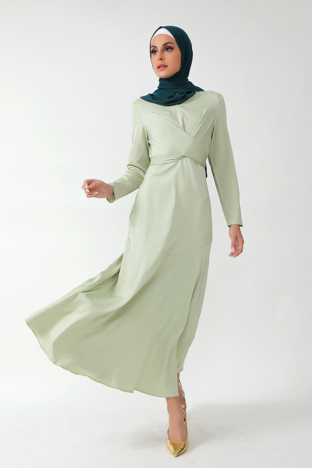 Woman in a light green dress and dark green hijab showcasing Sage Green Criss Cross Satin Maxi Dress