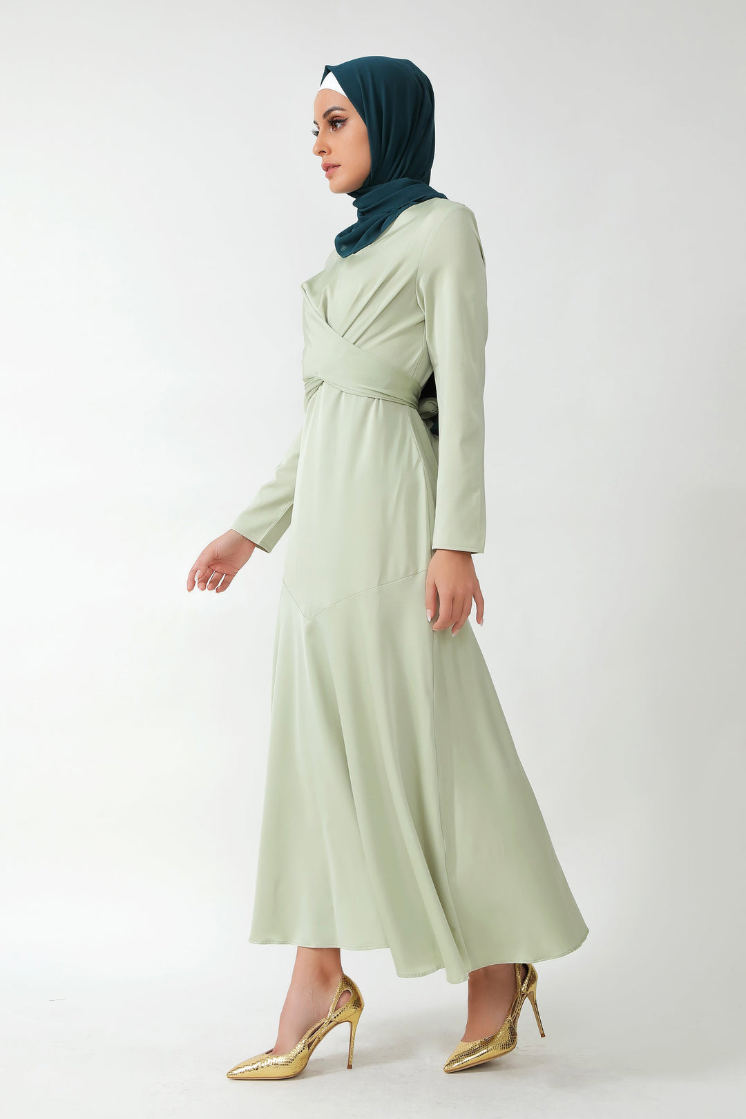 Woman in sage green criss cross satin long sleeve maxi dress with dark green hijab