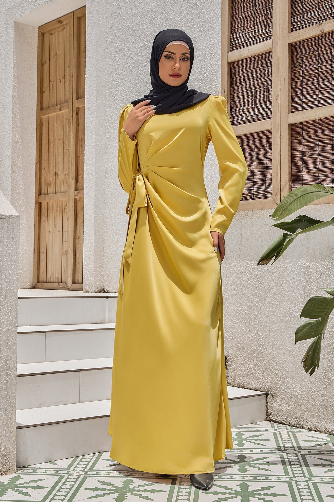 Woman in yellow satin faux wrap tie maxi dress with ruched waist and black hijab