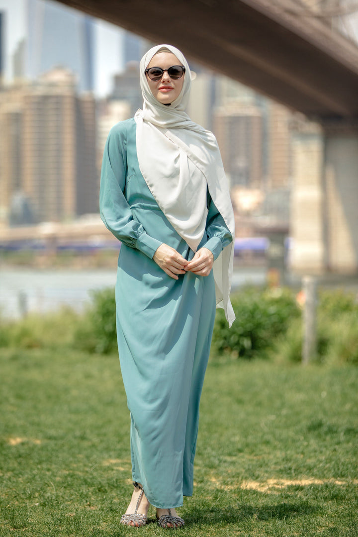 Woman in a sea blue wrap maxi dress with criss cross neckline and hijab