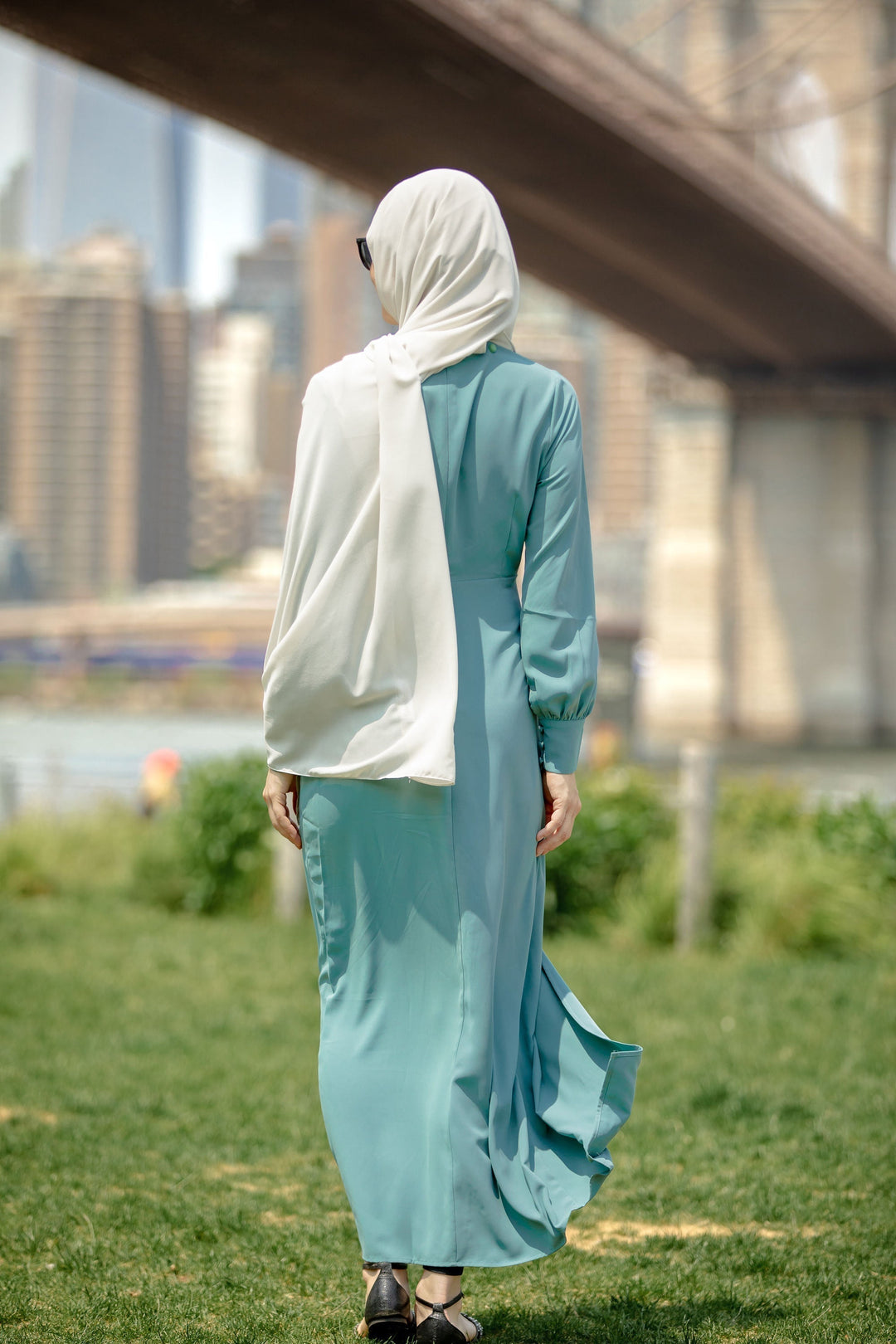 Woman in teal dress and hijab showcasing a Sea Blue Wrap Maxi Dress with criss cross neckline