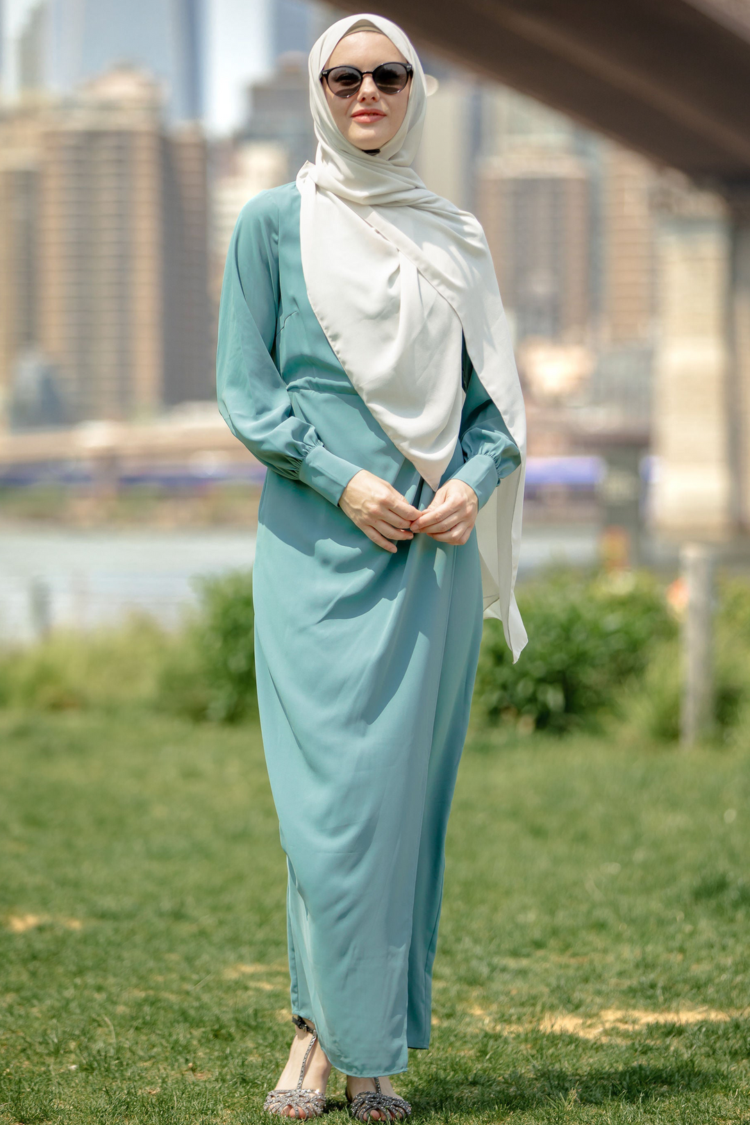 Woman in a teal dress and white hijab wearing a Sea Blue Wrap Maxi Dress with criss cross neckline