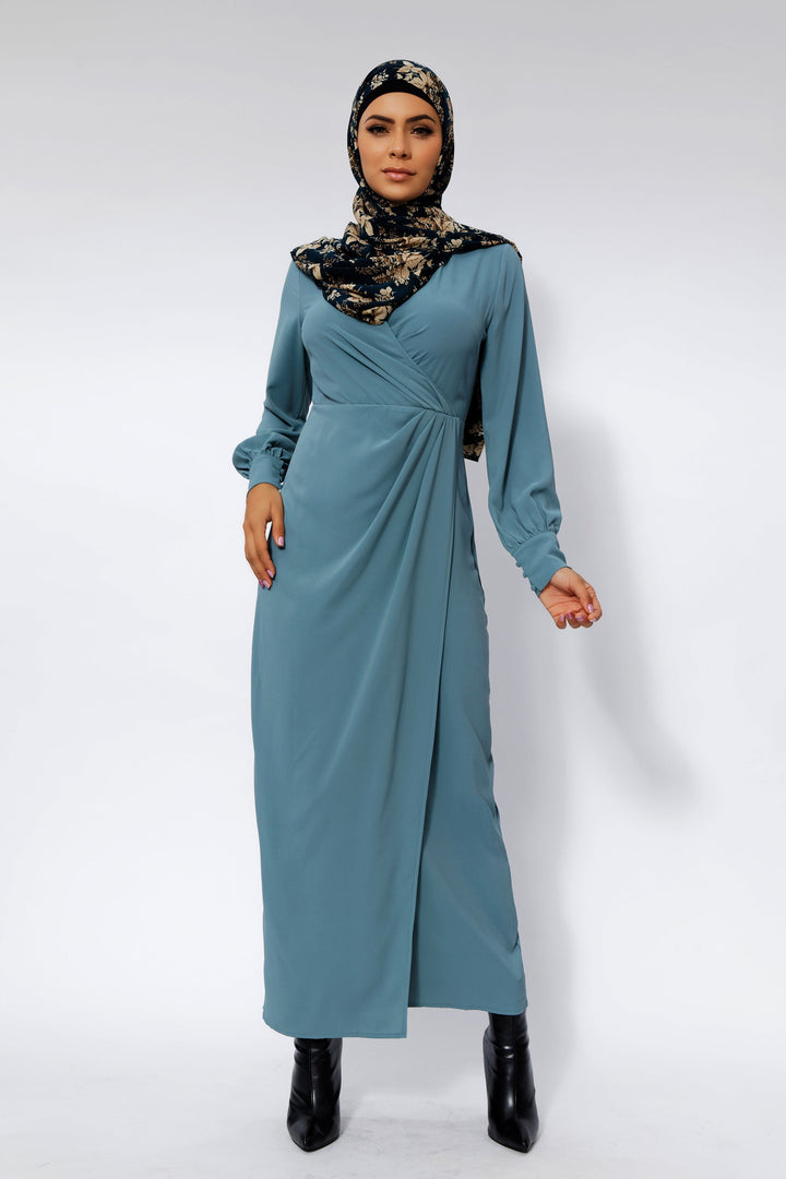 Woman wearing a sea blue wrap maxi dress with criss cross neckline and floral hijab