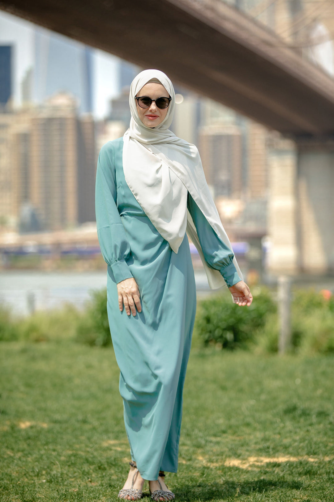 Woman in a teal dress and hijab wearing a sea blue wrap maxi dress with criss cross neckline