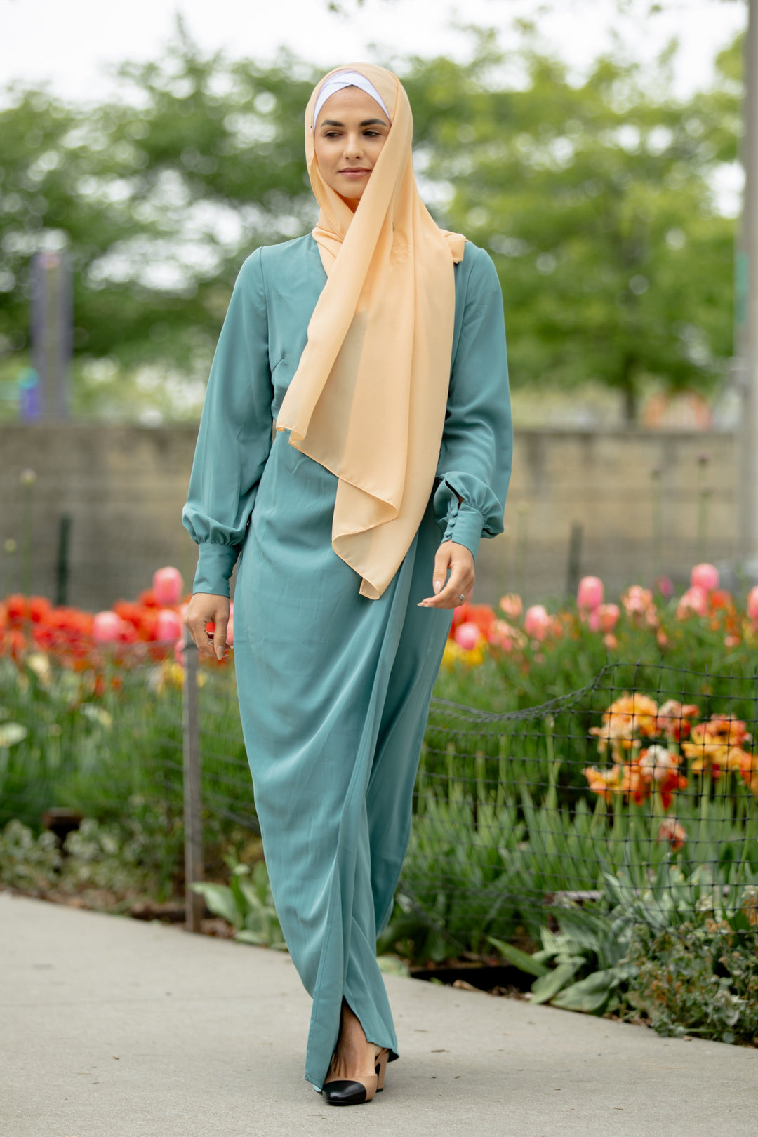 Woman in teal dress with peach hijab showcasing Sea Blue Wrap Maxi Dress with criss cross neckline