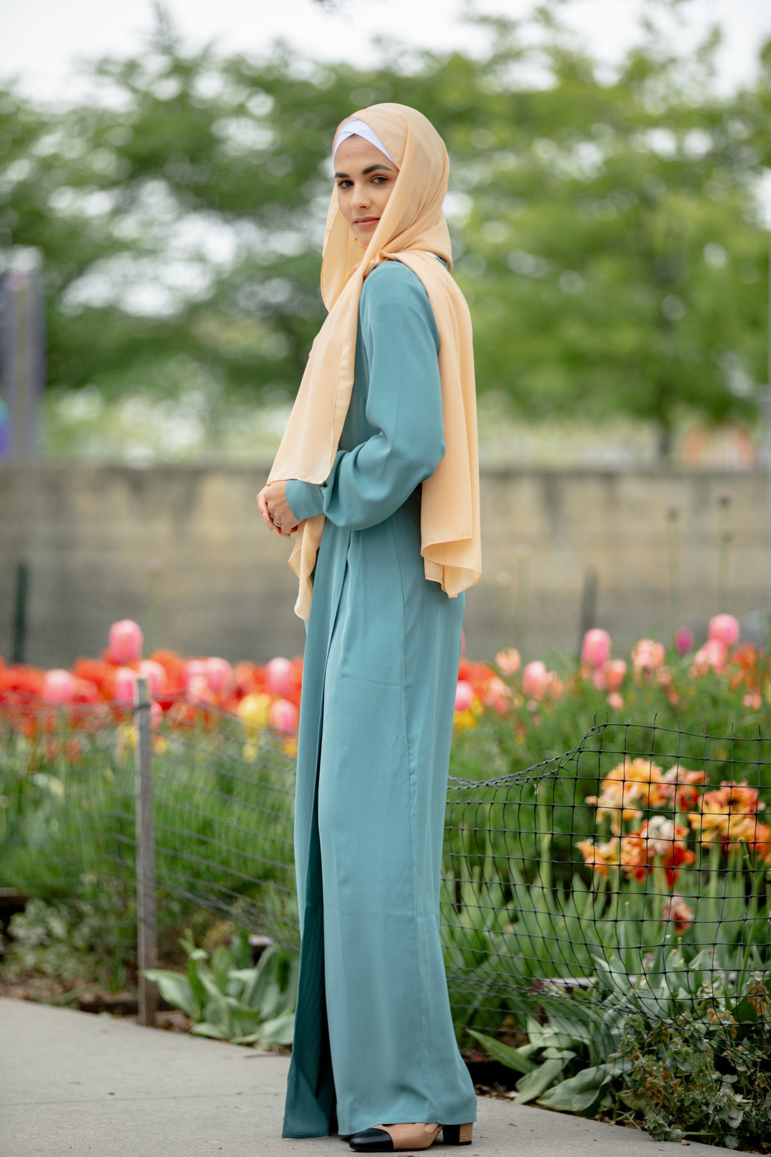 Woman wearing a Sea Blue Wrap Maxi Dress with criss cross neckline and peach hijab