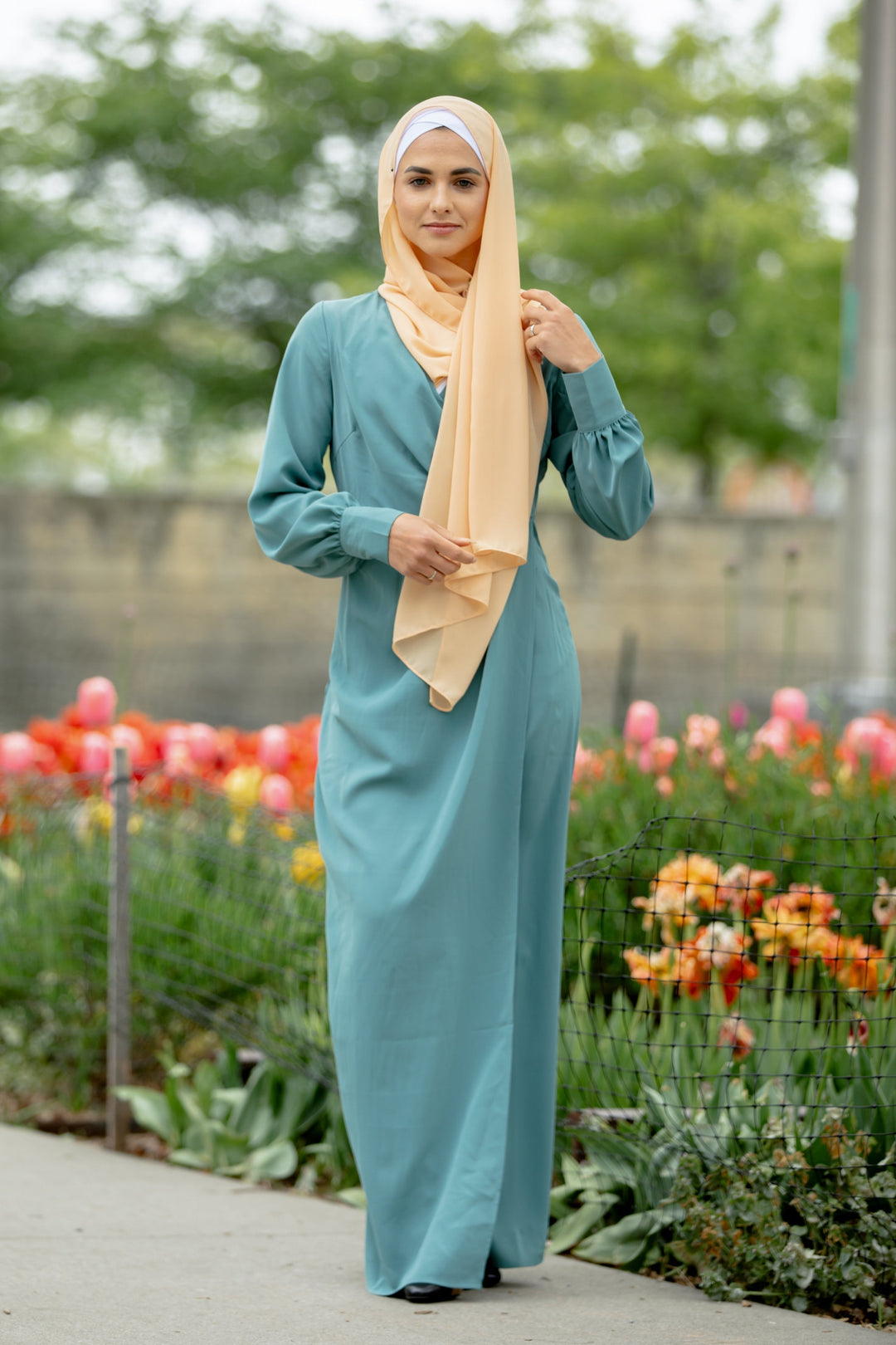 Woman in a teal dress with peach hijab showcasing a Sea Blue Wrap Maxi Dress