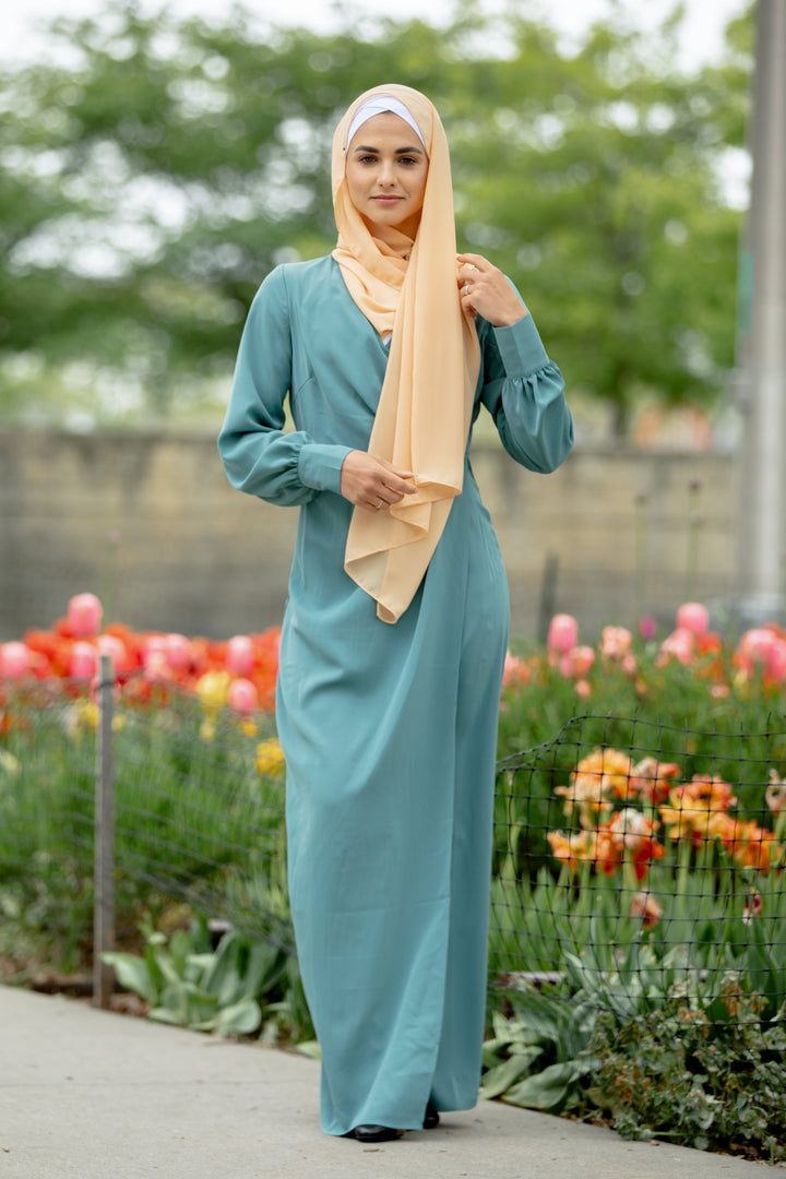 Woman in a teal dress with peach hijab showcasing a Sea Blue Wrap Maxi Dress