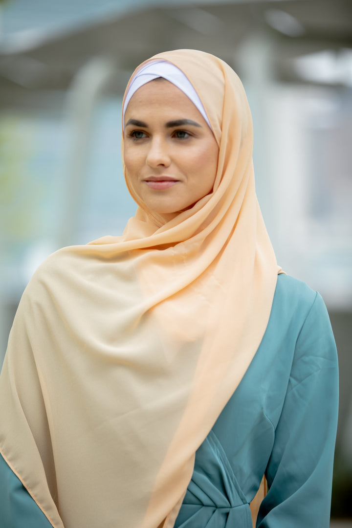 Woman in peach hijab showcasing a Sea Blue Wrap Maxi Dress with criss cross neckline