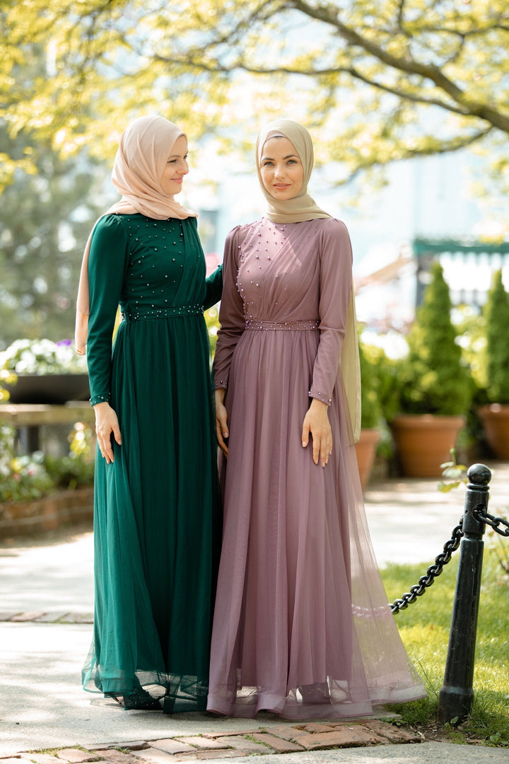 Two women in elegant hijabs wearing pearl gowns and long-sleeved maxi dresses