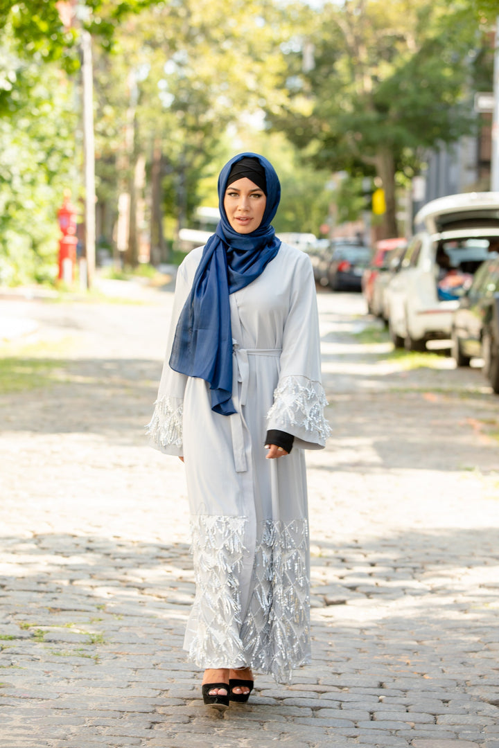 Woman in blue shimmer hijab and light gray abaya featuring silver sequin fringe