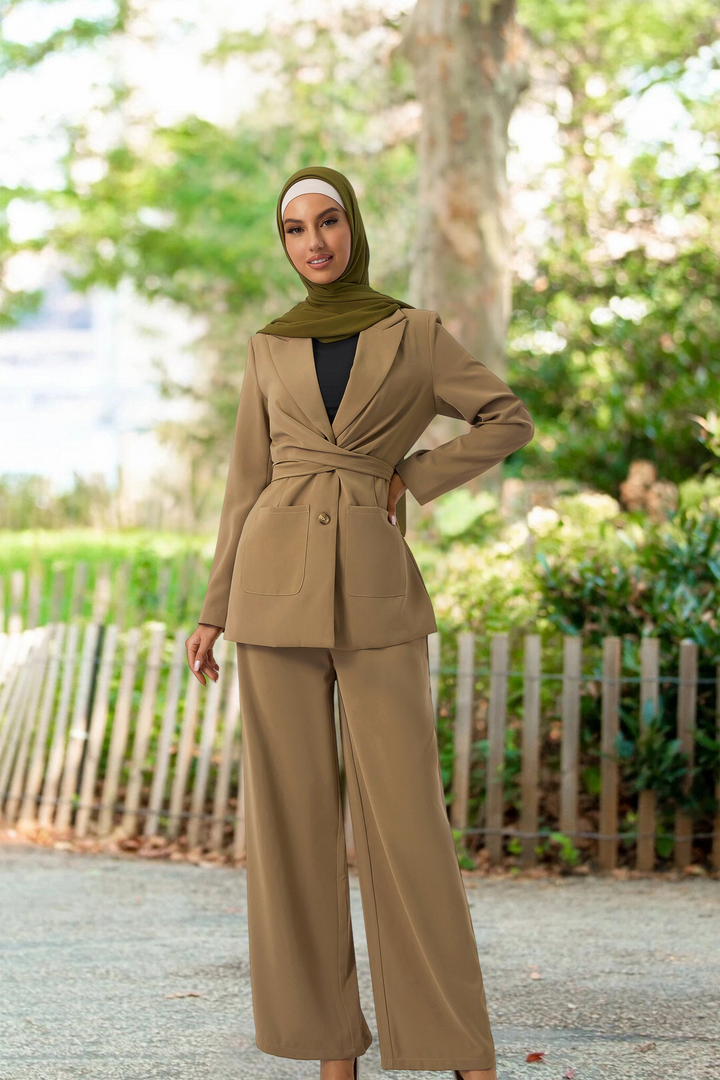 Woman in taupe jacket and pants suit, styled with a green hijab