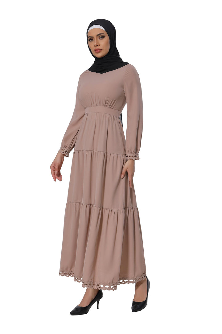 Woman wearing a taupe lace tiered maxi dress with a black hijab