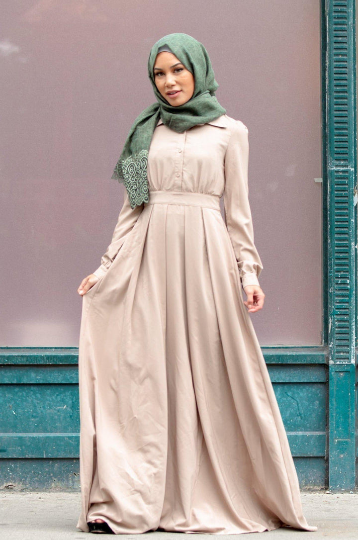 Woman in a beige dress with green hijab showcasing urban modesty and zipper closure