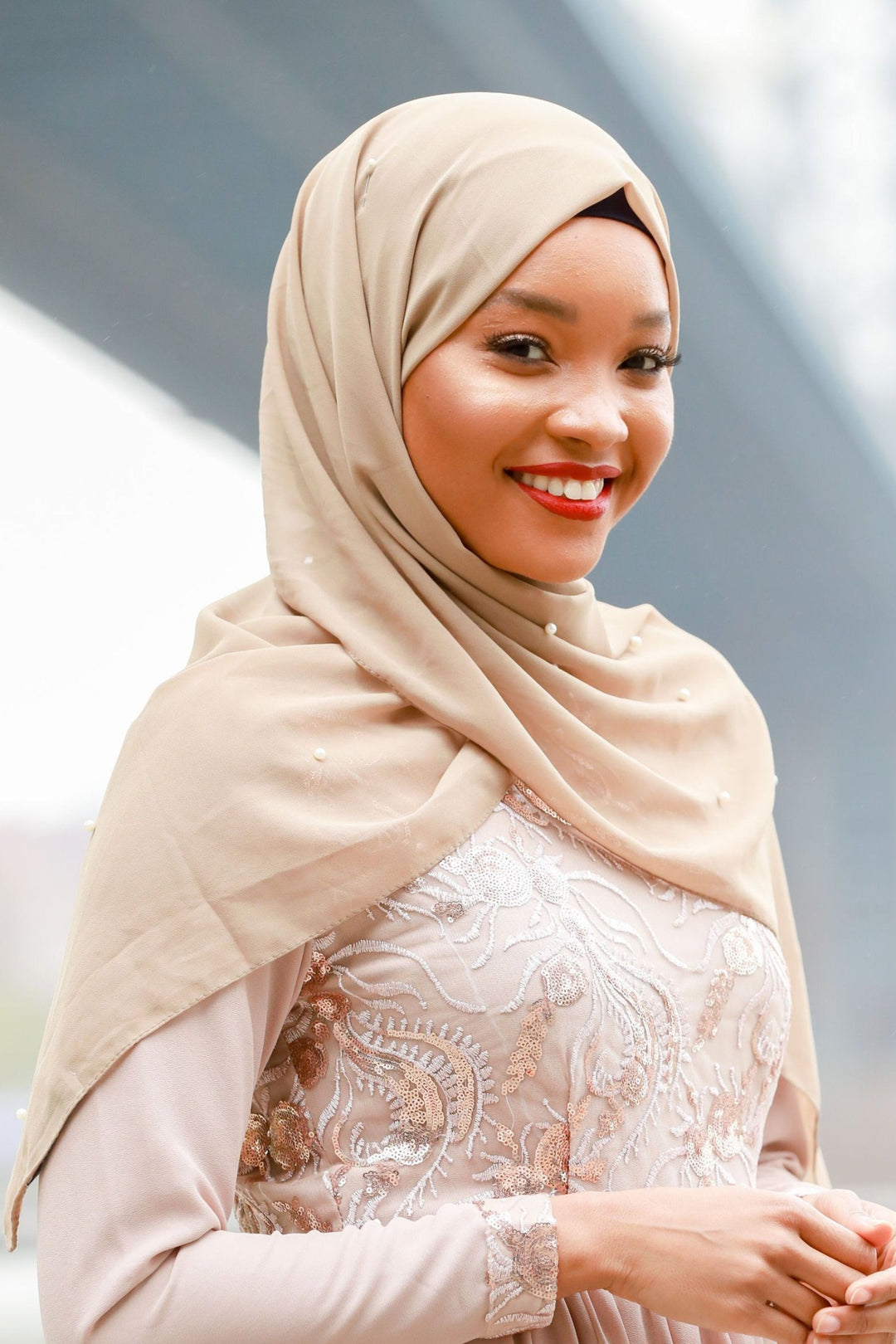 Smiling woman in taupe pearl chiffon hijab showcasing elegant style and versatility