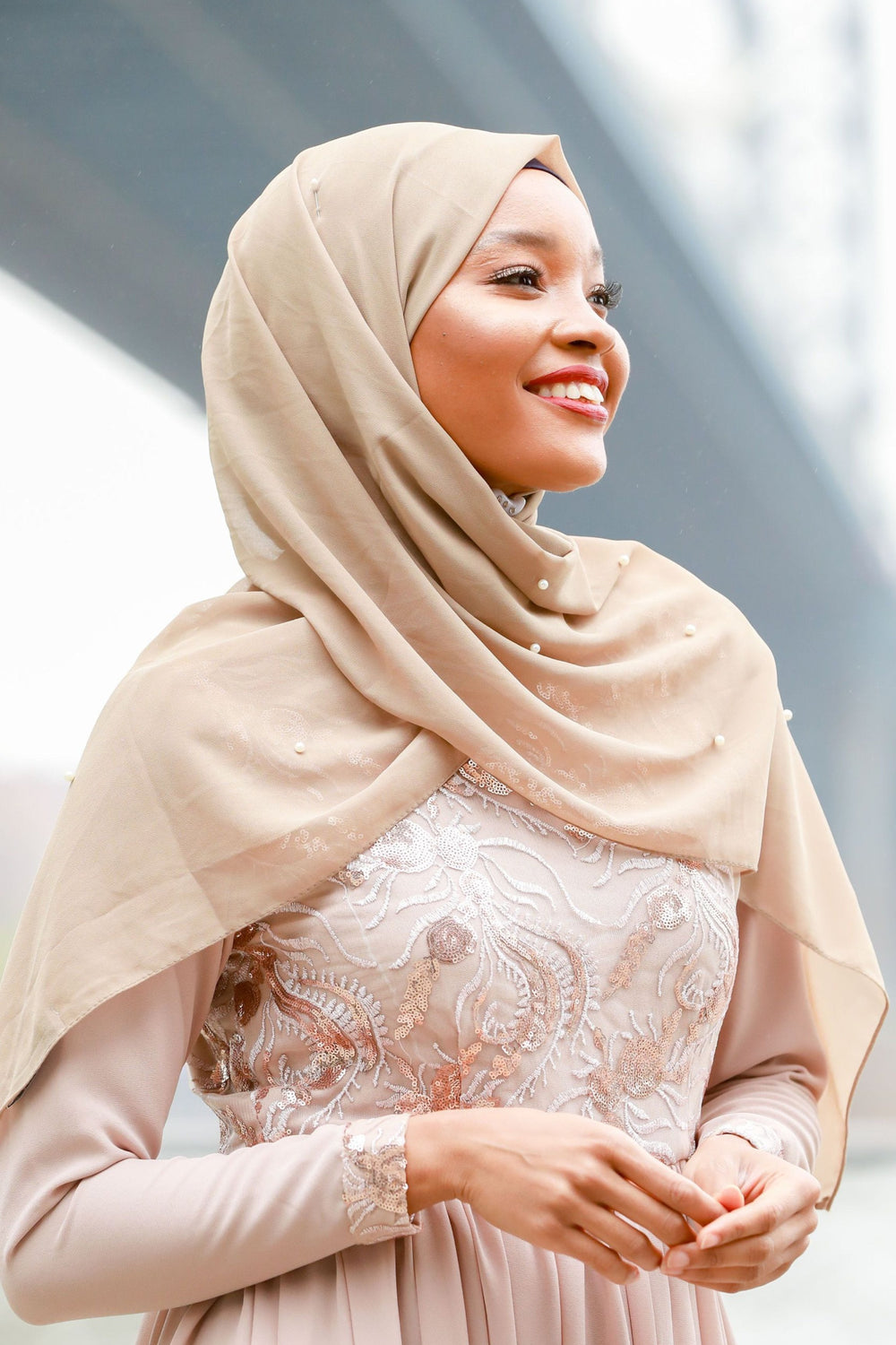 Smiling woman in hijab and elegant dress showcasing Taupe Pearl Chiffon Hijab