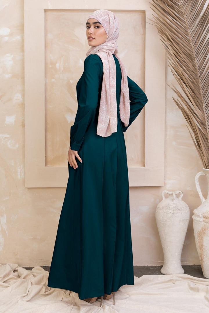 Emerald green long-sleeved dress with zipper closure and light pink hijab styling