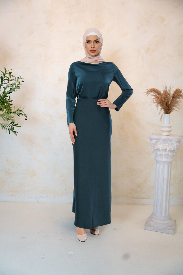 Woman wearing a teal satin long sleeve skirt set with a matching hijab