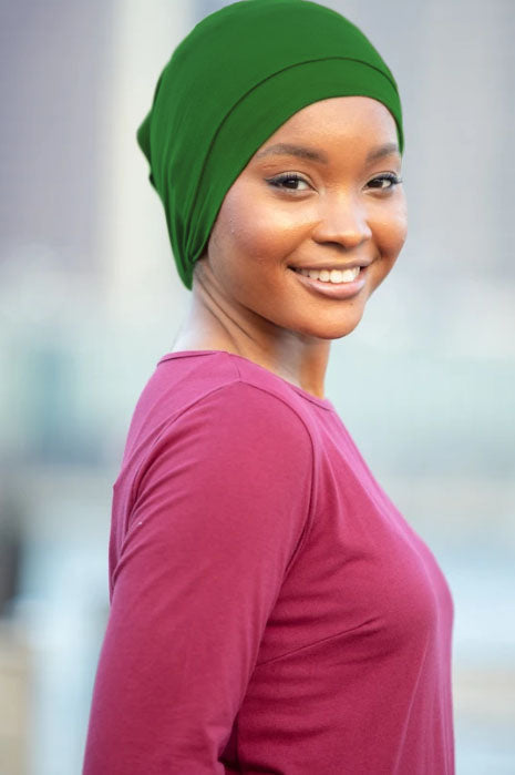 Smiling woman wearing tube hijab underscarf in green and maroon outfit