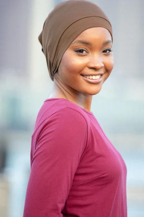 Smiling woman in brown headscarf and maroon shirt showcasing tube hijab underscarf