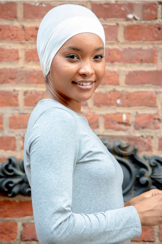 Woman in white head covering and gray shirt wearing a tube hijab underscarf