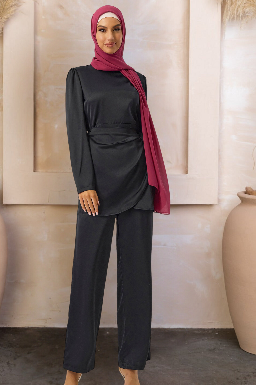 Woman in black satin side wrap tunic and pant set with red hijab
