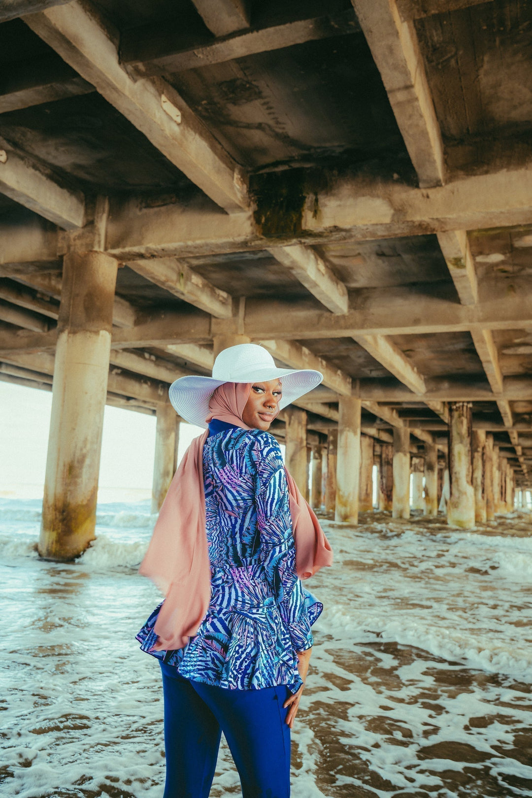 Woman in navy floral ruffle 3-piece modest swimsuit on beach