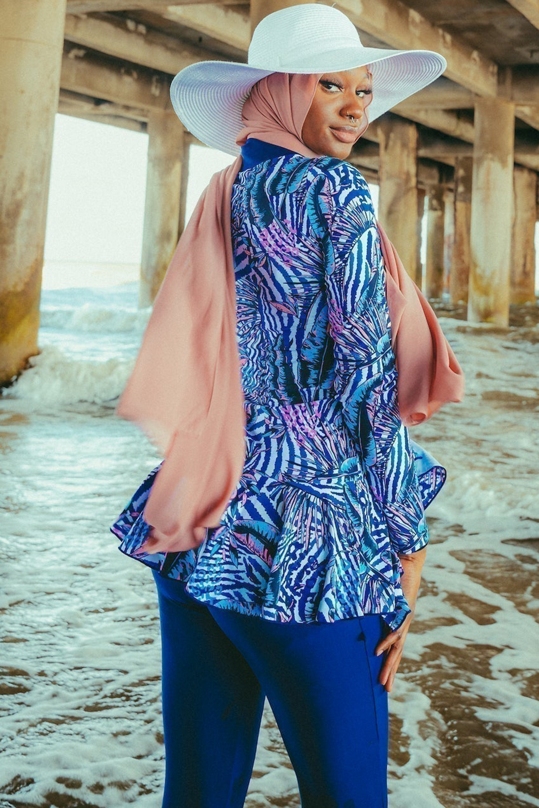 Woman in navy floral ruffle 3-piece modest swimsuit with hijab and sun hat