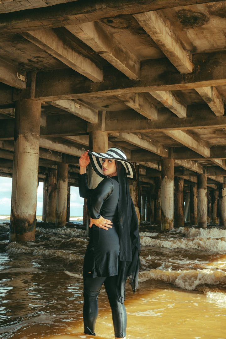 Woman in black ruched 3-piece modest swimsuit with striped hat
