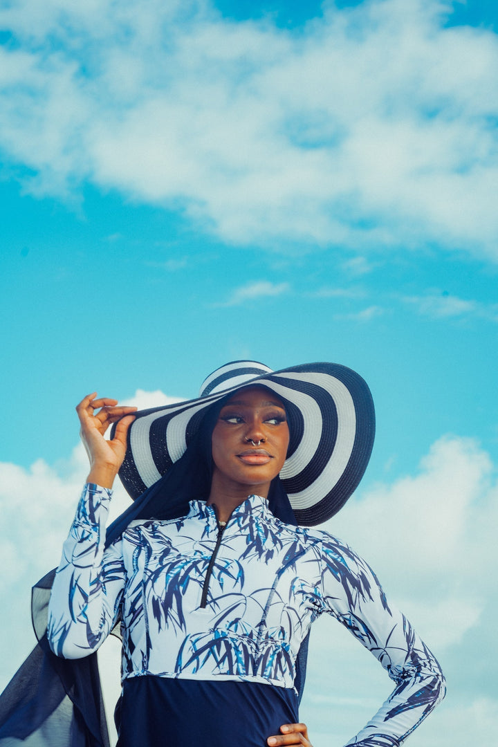 Woman in striped hat and patterned rash guard in white and navy floral modest swimsuit