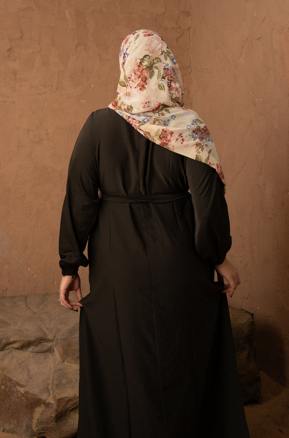 a woman in a black dress with a floral scarf on her head