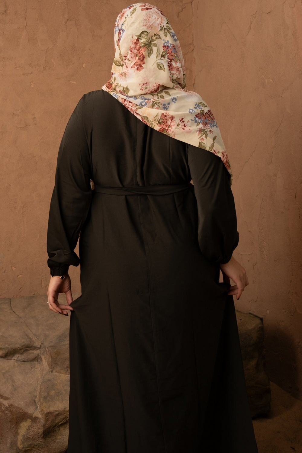 a woman in a black dress with a floral scarf on her head