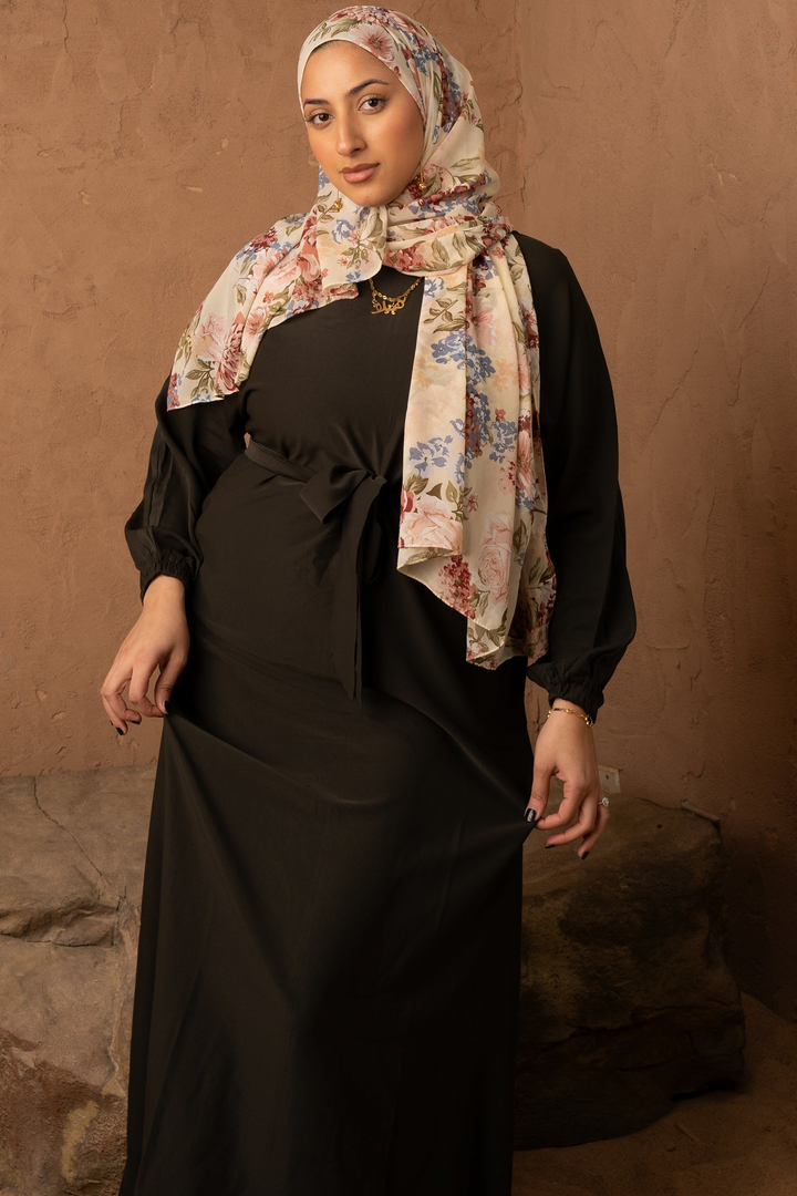 a woman wearing a black dress and a floral scarf