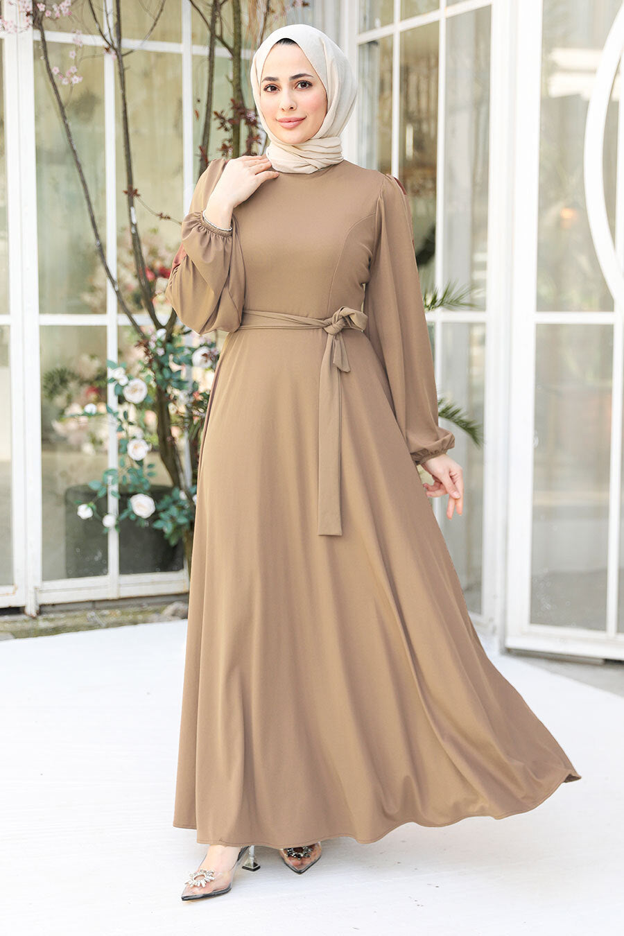 a woman wearing a brown dress and a hijab
