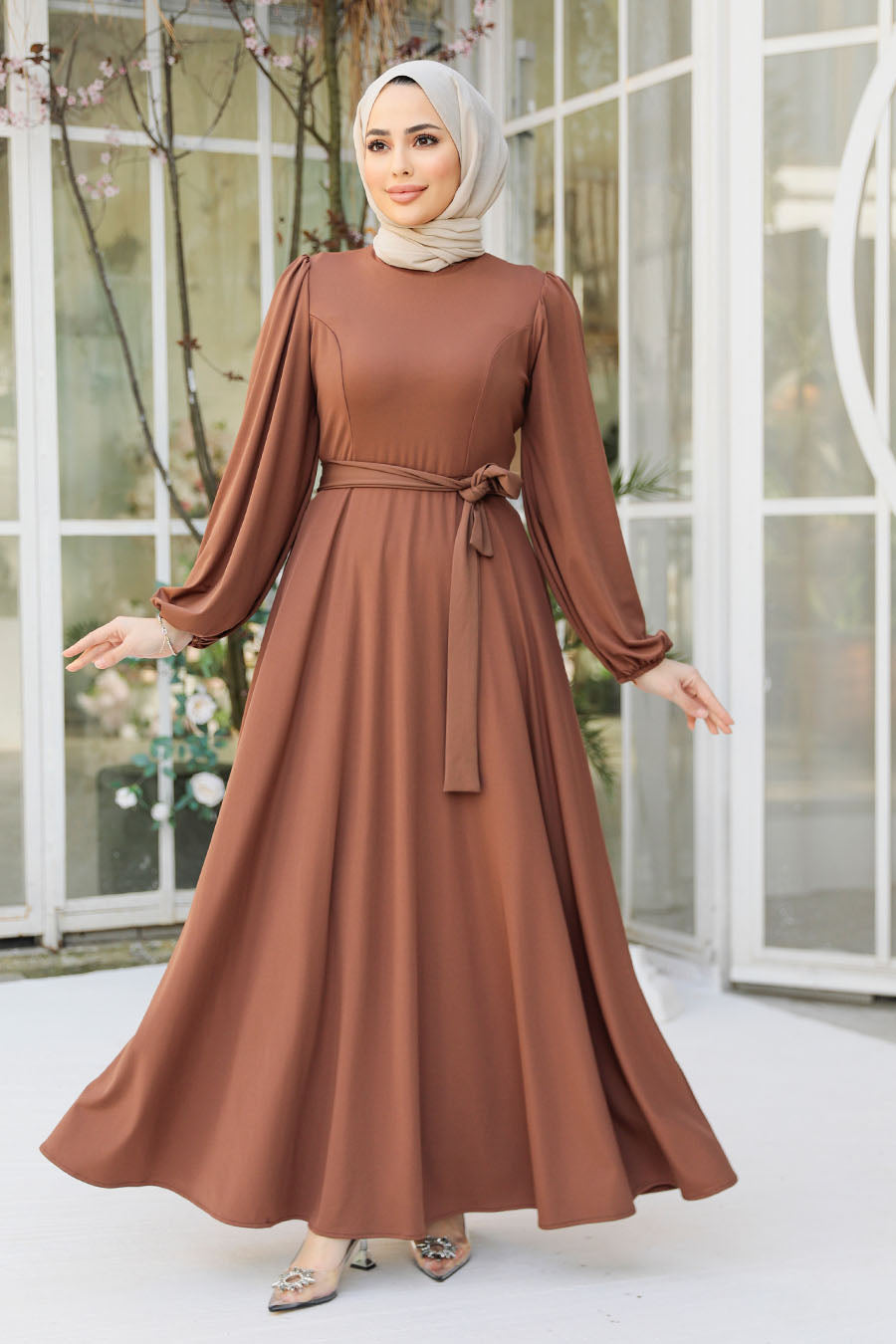 a woman wearing a brown dress and hijab