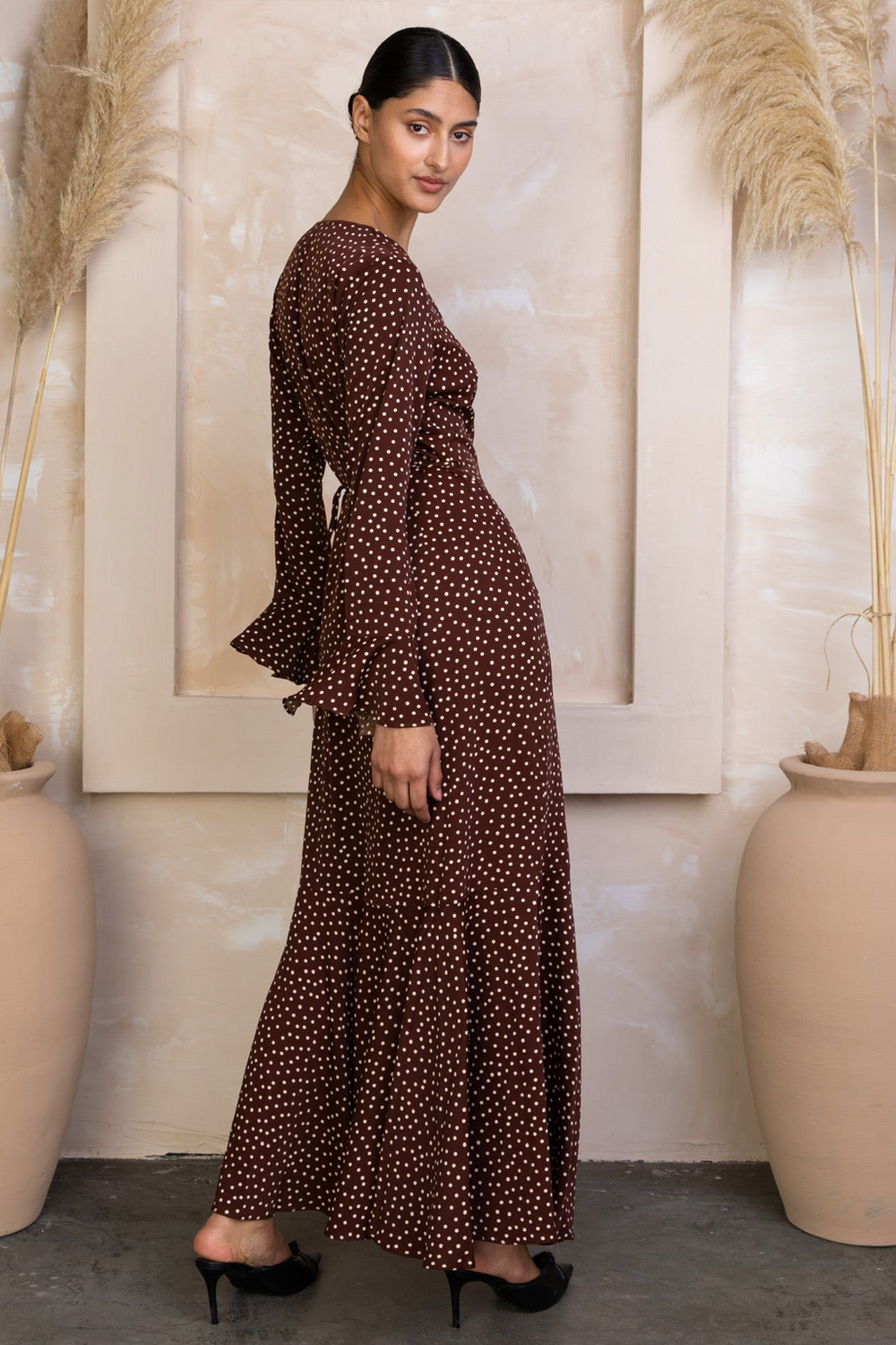 a woman standing in front of a wall wearing a dress