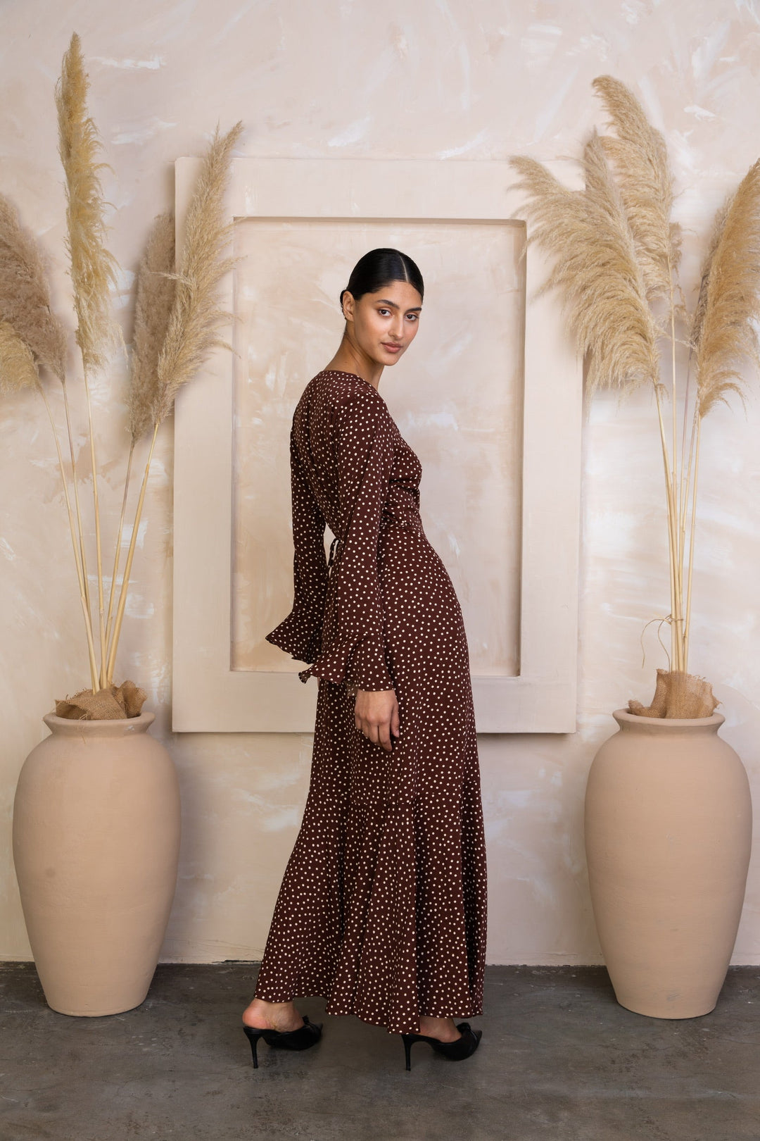 a woman standing in front of two large vases