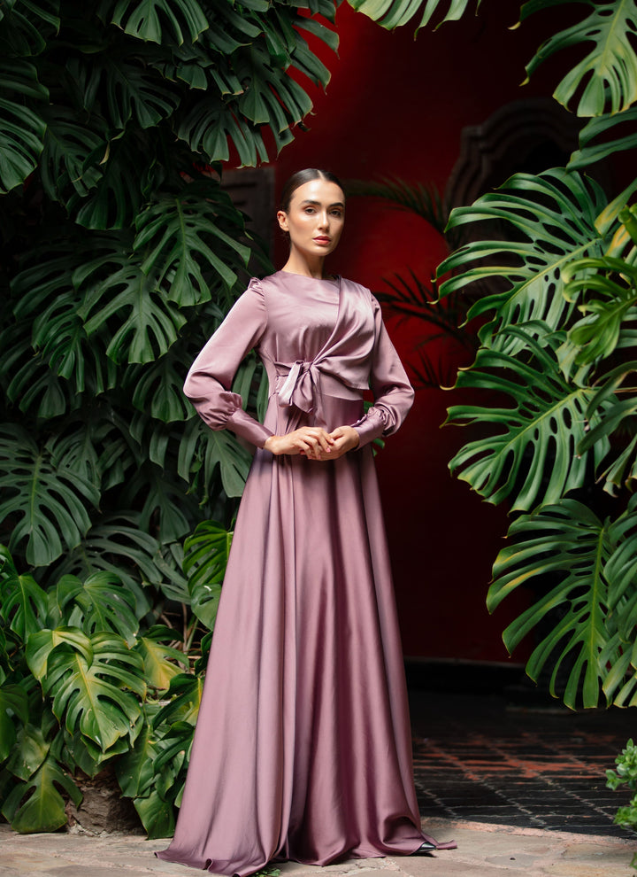 a woman in a long dress standing in front of plants