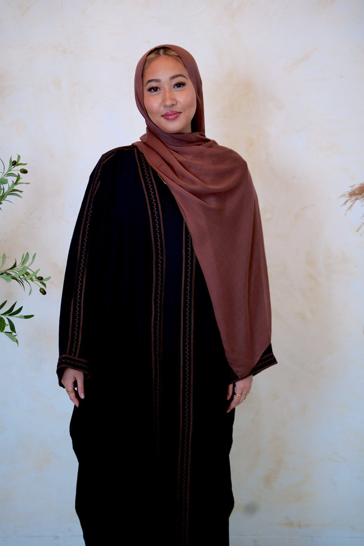 a woman in a black dress and a brown shawl