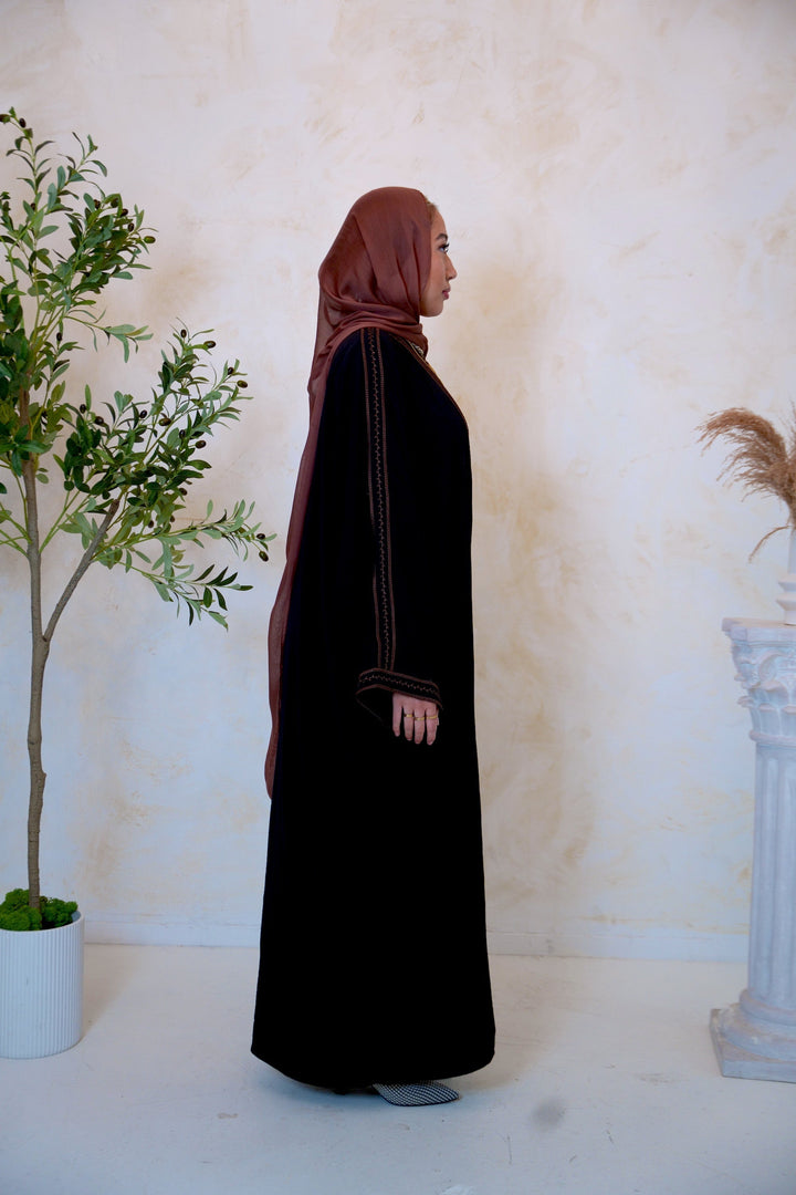 a woman in a black hijab standing in front of a tree