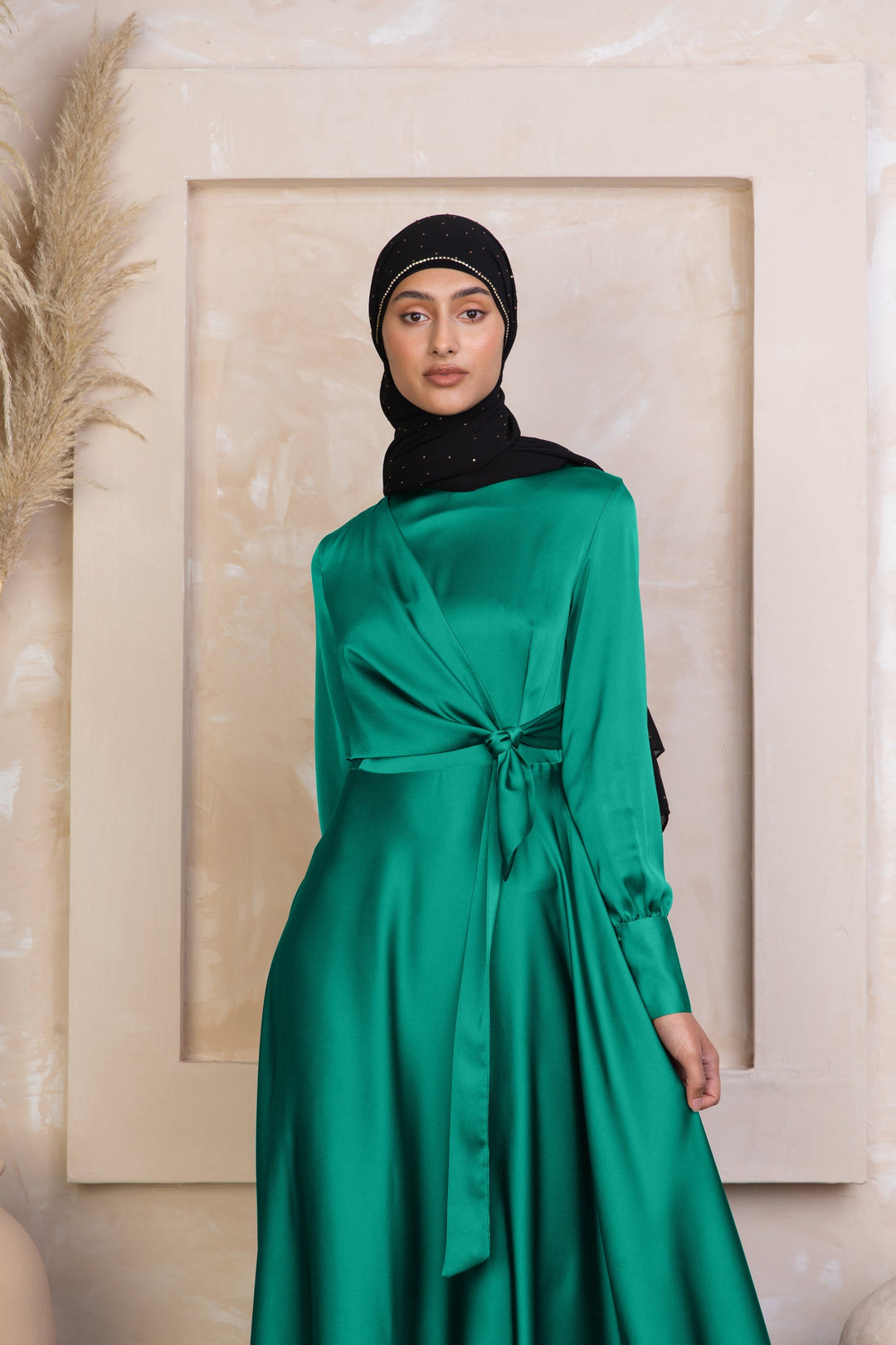 a woman wearing a green dress with a black head scarf