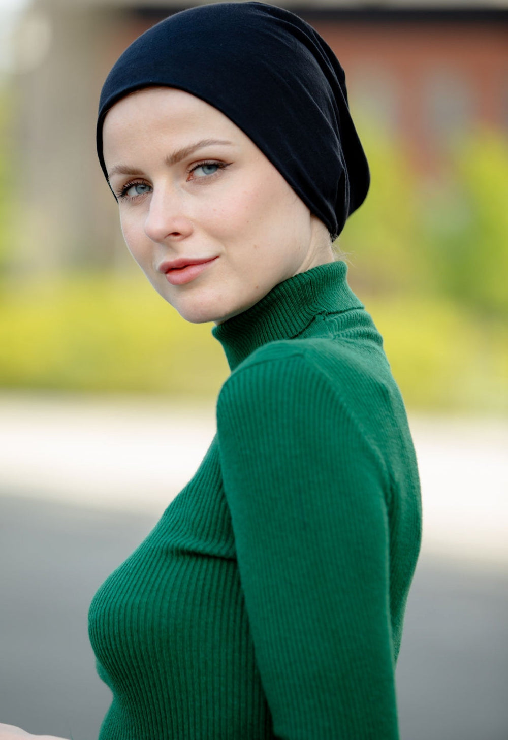 a woman wearing a green sweater and a black head scarf