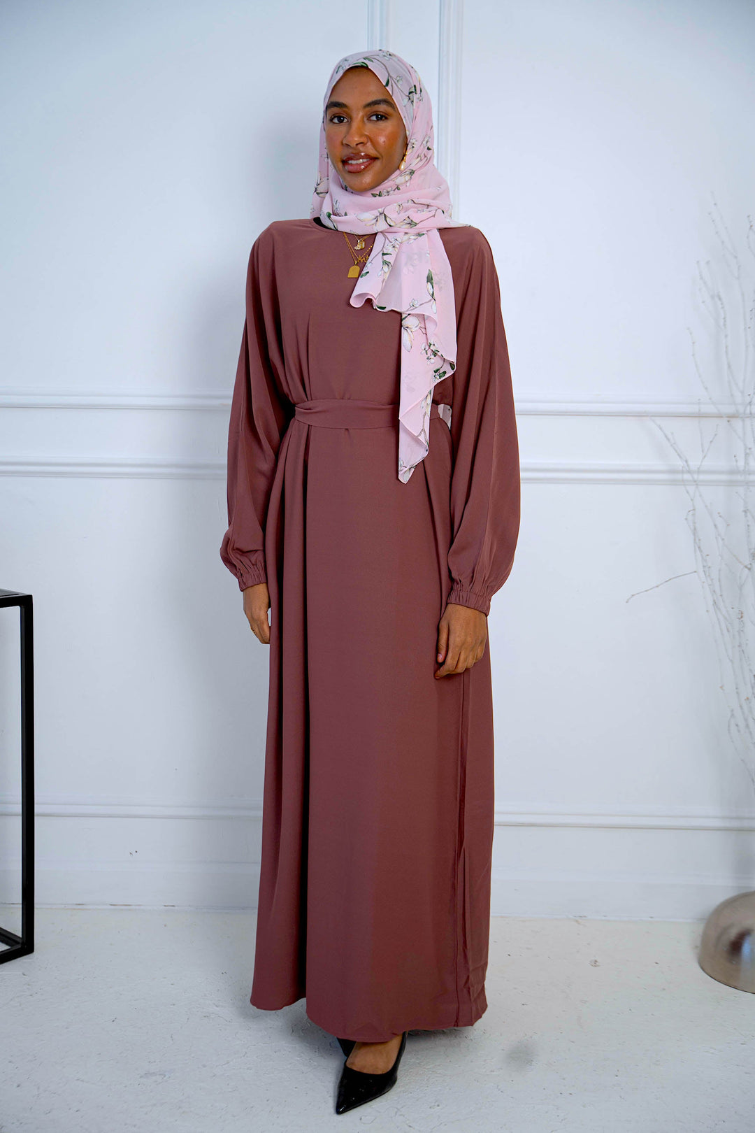 a woman in a brown dress and a pink scarf