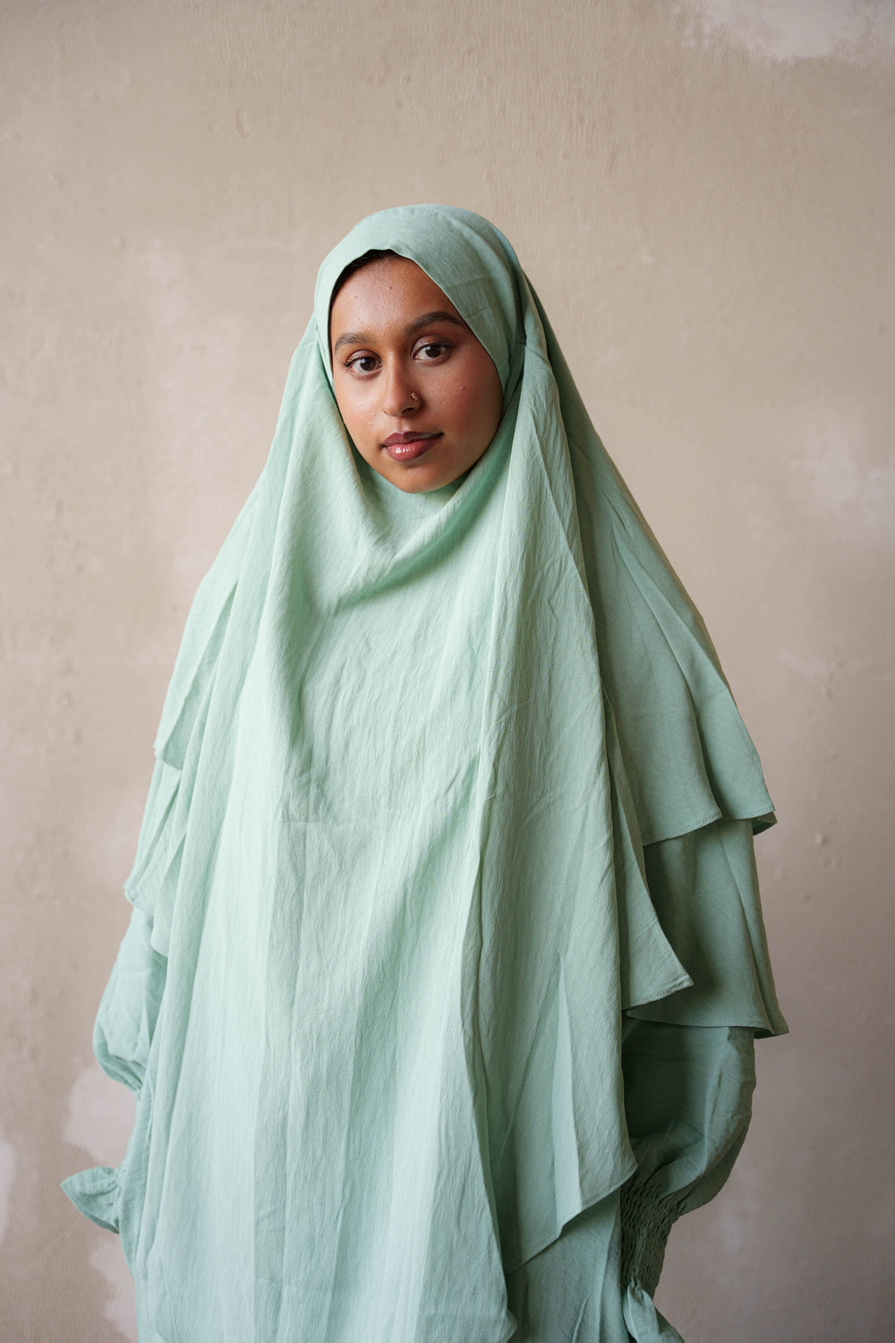 a woman in a green hijab poses for a picture